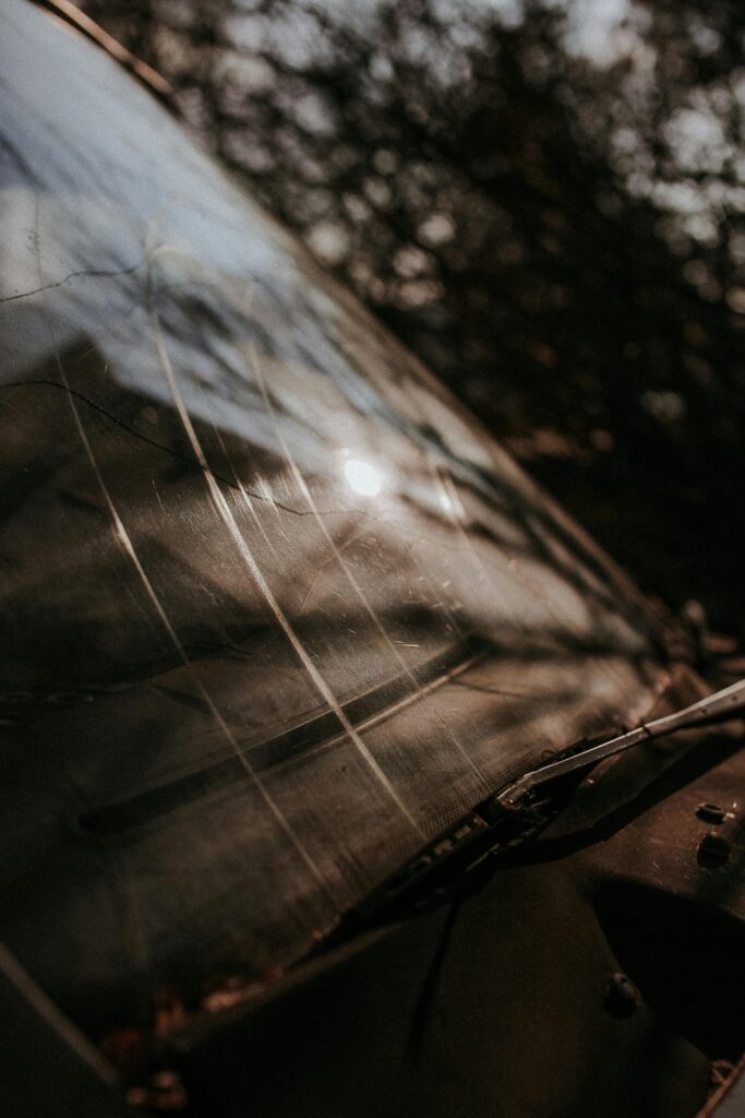 Close-up of a dirty car windshield reflecting cloudy sky. Moody and atmospheric shot.